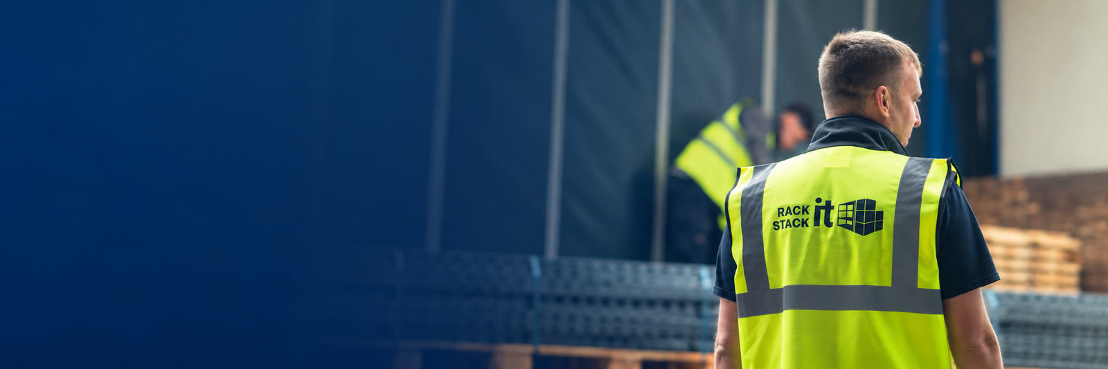 Rack It Stack It installer in a branded hi-vis vest on site with racking components ready to load
